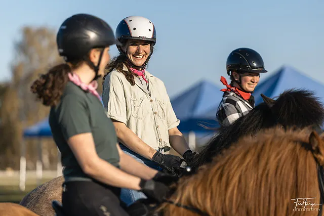Lachende Reitschülerinnen mit Helm auf ihren Islandpferden